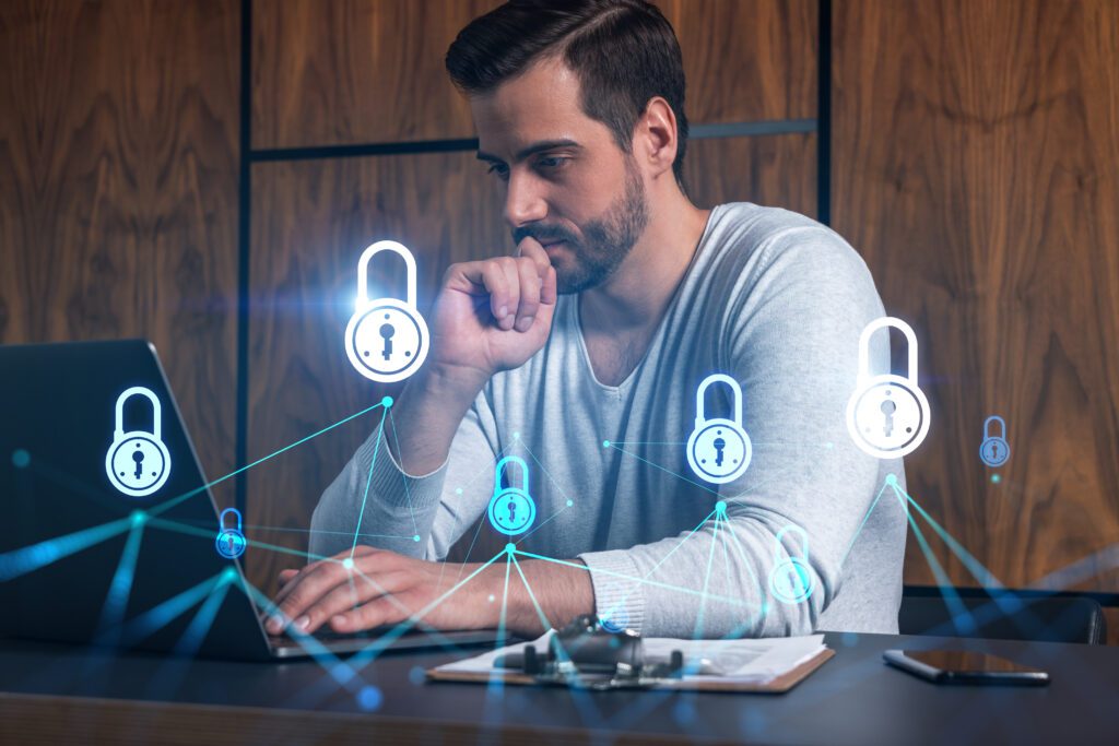 A male employee sitting in front of the laptop and working on recovering data during outages or upgrades.